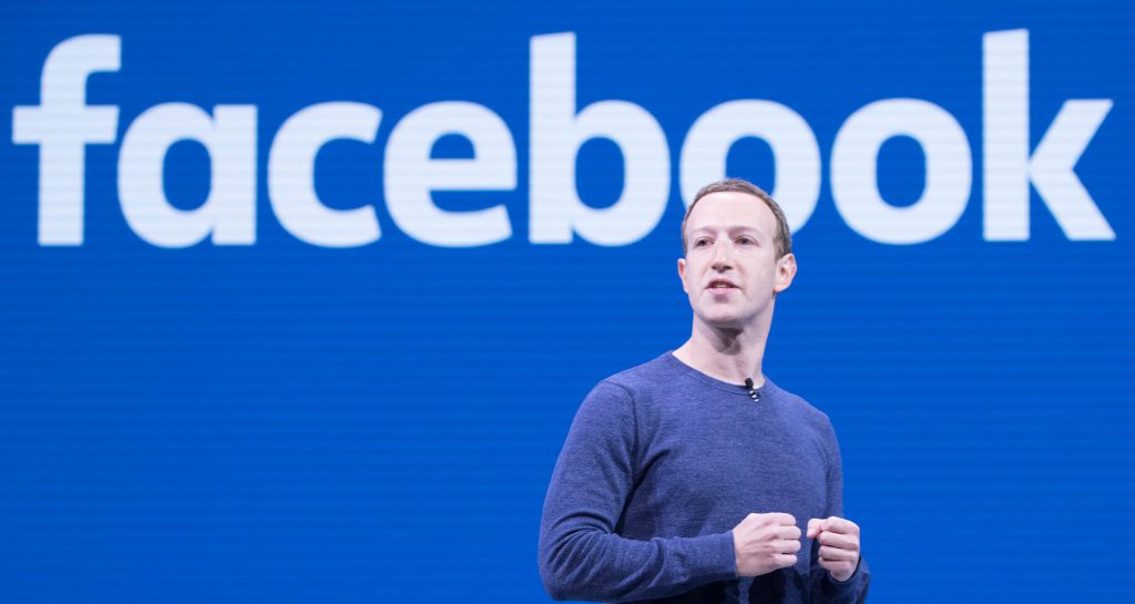 Mark Zuckerberg gives a presentation in front of Facebook logo
