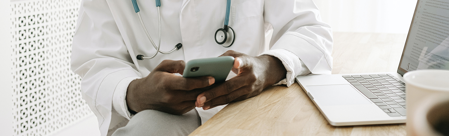 A Man Wearing a Medical Gown Using a Smartphone